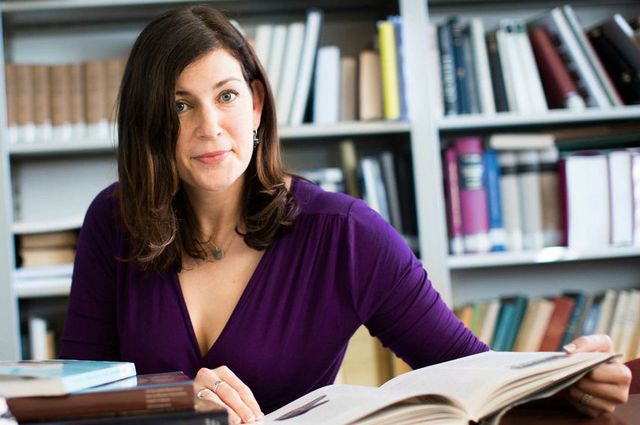 Kara Cooney at her desk paging through an open book