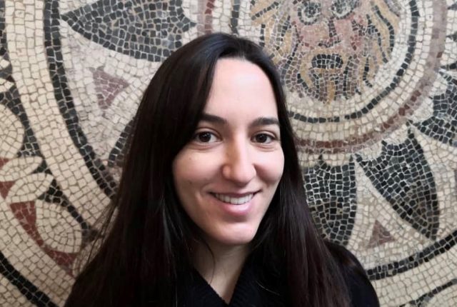 Adriana Vazquez smiles in a selfie against a mosaic background.