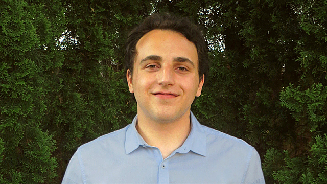 Joseph Matveyenko smiles at the camera in an outdoor portrait.