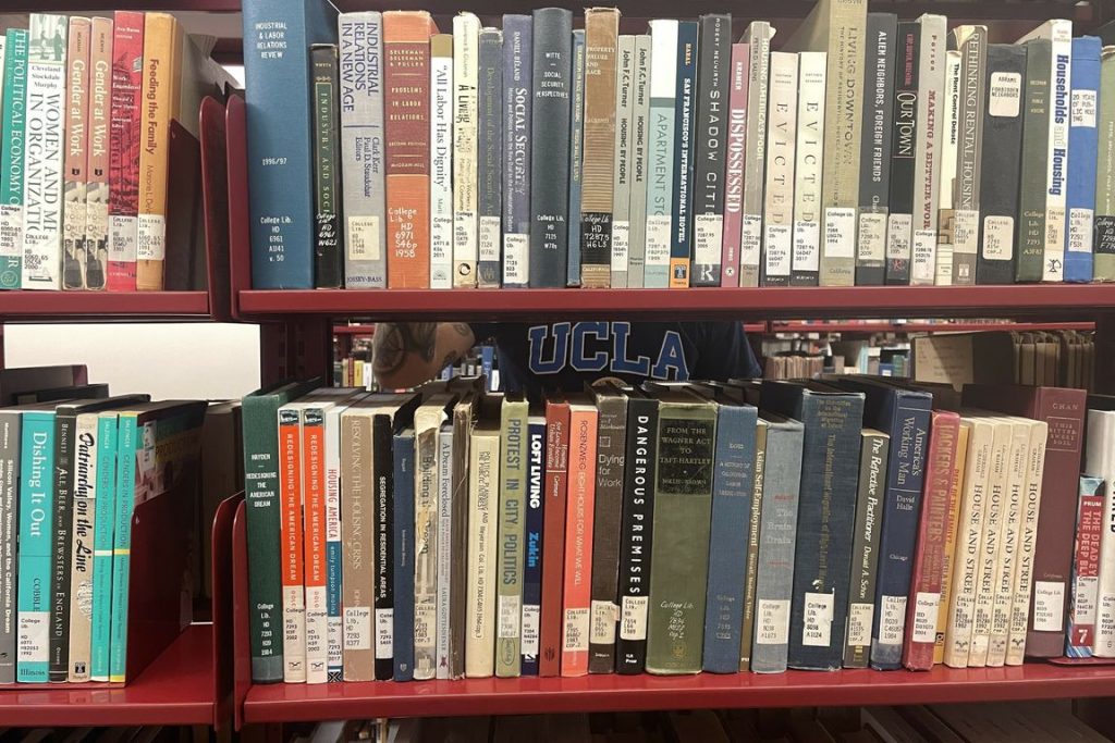 A red bookshelf in the Young Research library holds books of many colors and sizes.