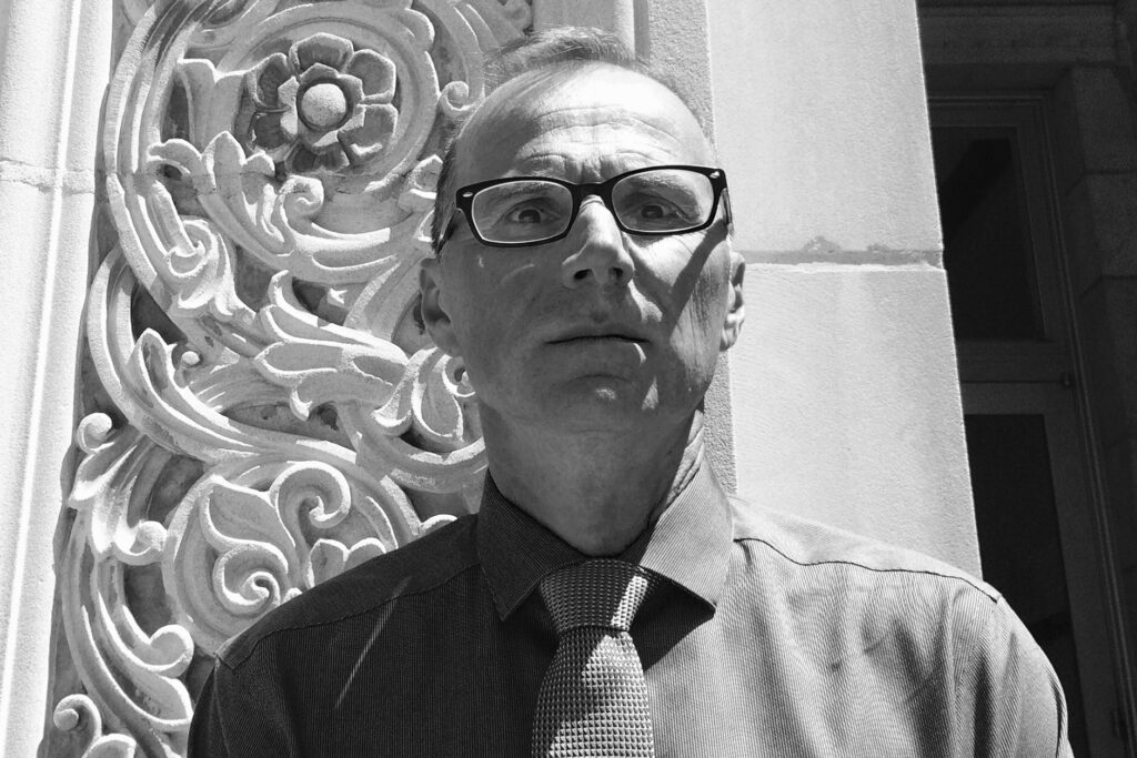 Black and white photo of Robert Gurval in front of a UCLA campus building