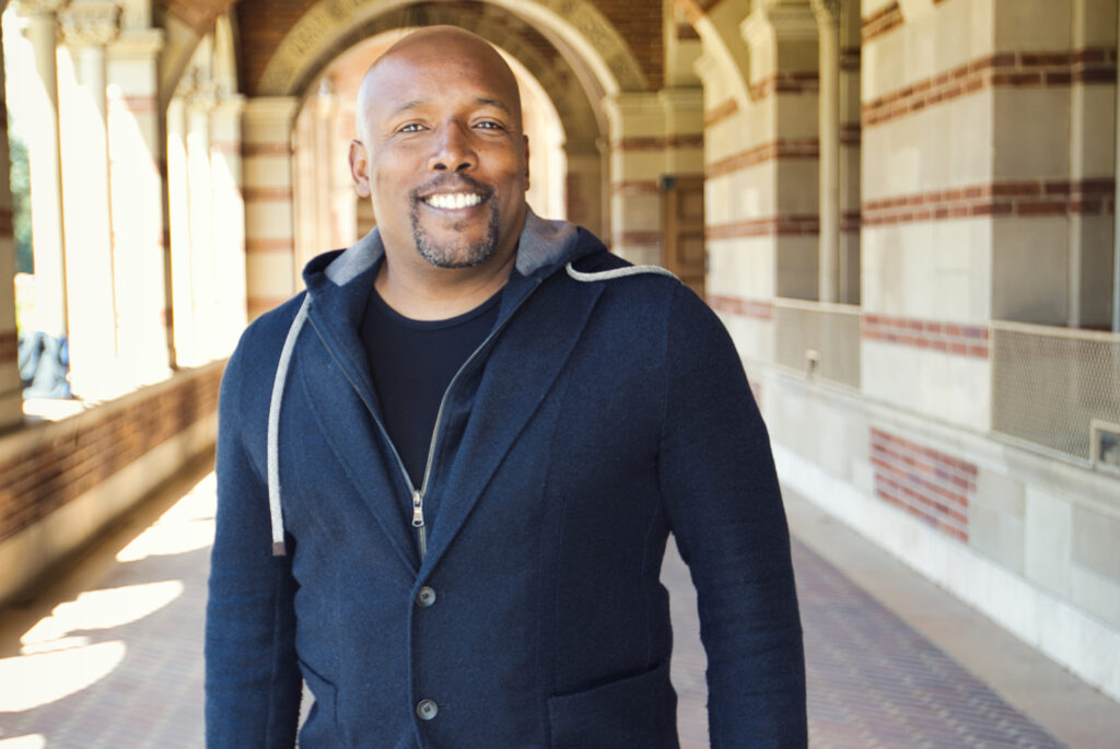 Kwame J. Granderson wearing blue jacket standing under the Royce Hall arches